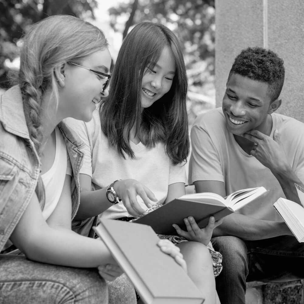 Three teens holding books study out side, black and white image